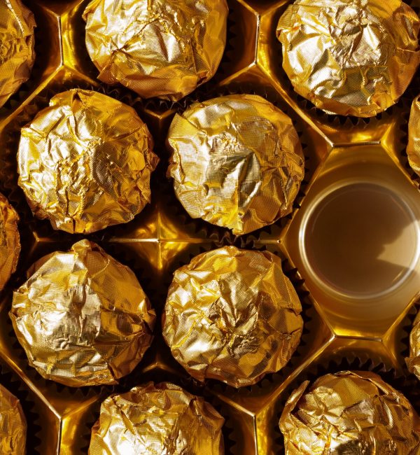 Chocolate balls in gold foil view from the top, with one empty place in candy box