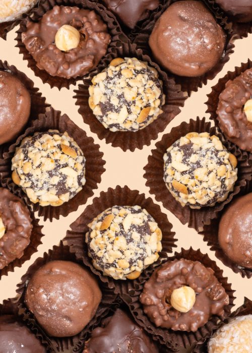 Chocolate craft nuts candies on beige background flat lay, top view.