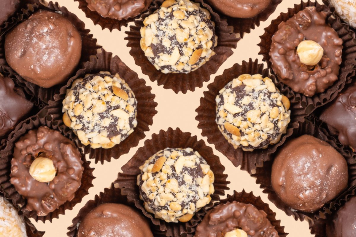 Chocolate craft nuts candies on beige background flat lay, top view.